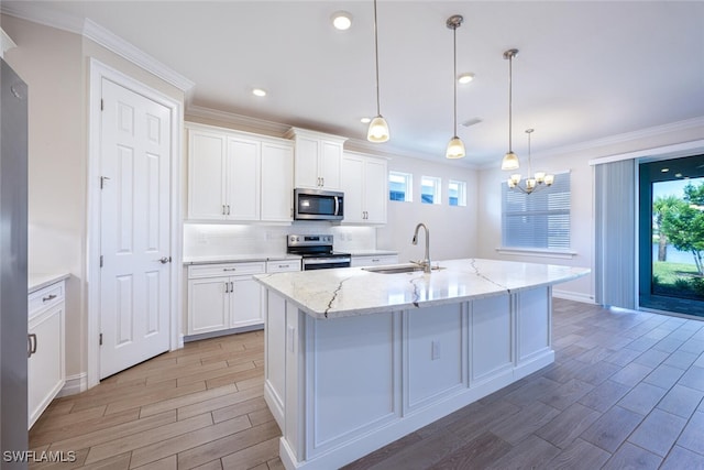 kitchen featuring a kitchen island with sink, pendant lighting, white cabinets, and stainless steel appliances