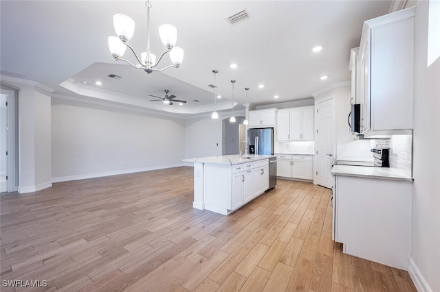 kitchen with ceiling fan with notable chandelier, stainless steel appliances, a raised ceiling, white cabinets, and hanging light fixtures