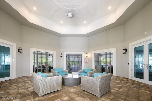 living room featuring a healthy amount of sunlight, a raised ceiling, a high ceiling, and french doors