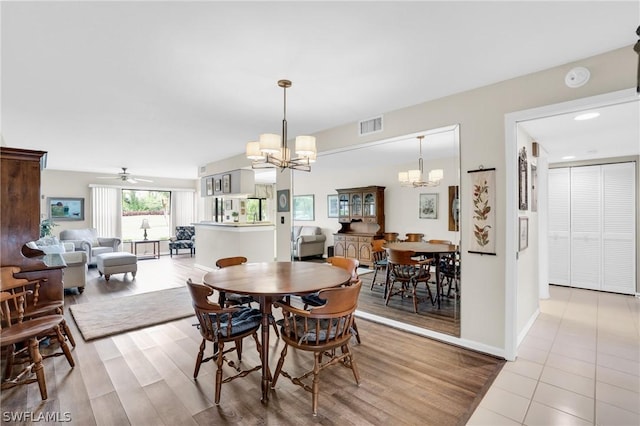 dining space featuring ceiling fan with notable chandelier