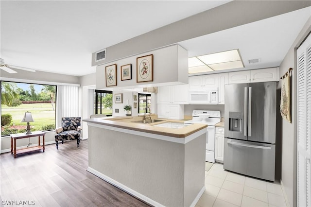 kitchen with white appliances, kitchen peninsula, ceiling fan, sink, and white cabinetry