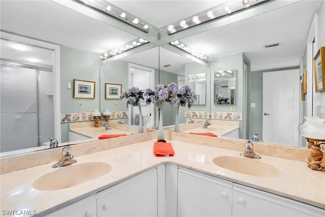 bathroom featuring a shower with door and vanity