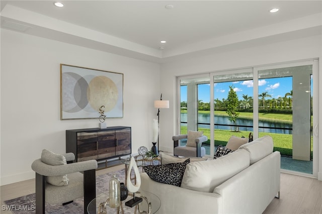 living room with light hardwood / wood-style flooring and a water view