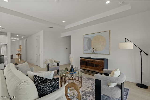 living room featuring a tray ceiling and light wood-type flooring