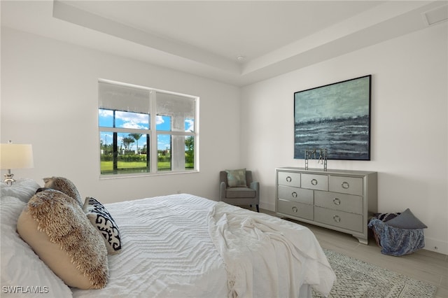 bedroom featuring a raised ceiling and light wood-type flooring