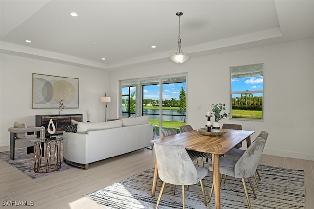 dining space with a tray ceiling and a water view