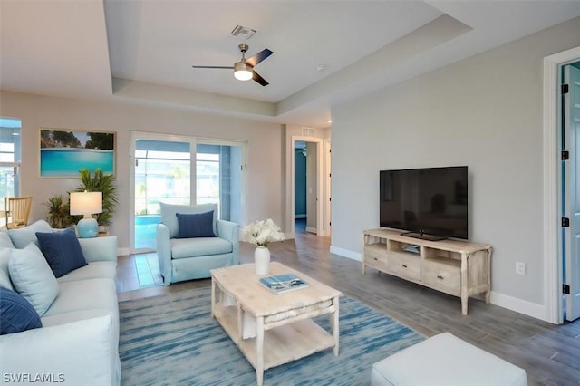 living room featuring hardwood / wood-style floors, a tray ceiling, a wealth of natural light, and ceiling fan