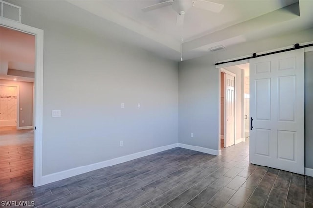 unfurnished room featuring dark wood-type flooring, ceiling fan, and a barn door