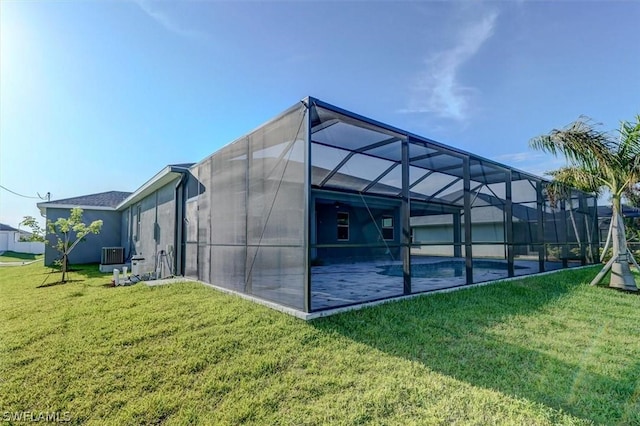 back of property featuring central air condition unit, glass enclosure, and a lawn