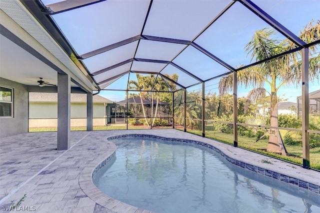 view of pool with a patio, ceiling fan, and glass enclosure