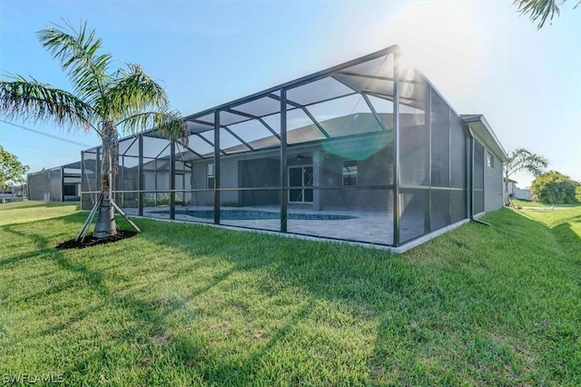 back of house featuring a patio area, glass enclosure, and a lawn