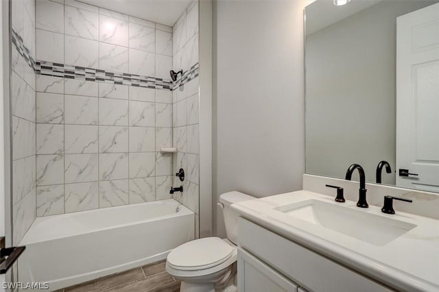 full bathroom featuring tiled shower / bath, vanity, and toilet