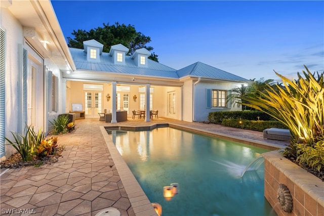 pool at dusk with french doors and a patio