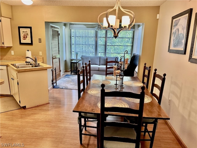 dining space featuring a notable chandelier, sink, light hardwood / wood-style flooring, and a textured ceiling