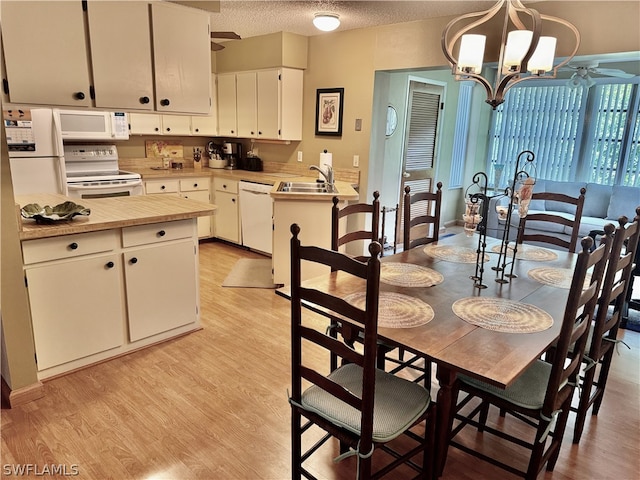 dining space featuring ceiling fan with notable chandelier, light hardwood / wood-style flooring, a textured ceiling, and sink