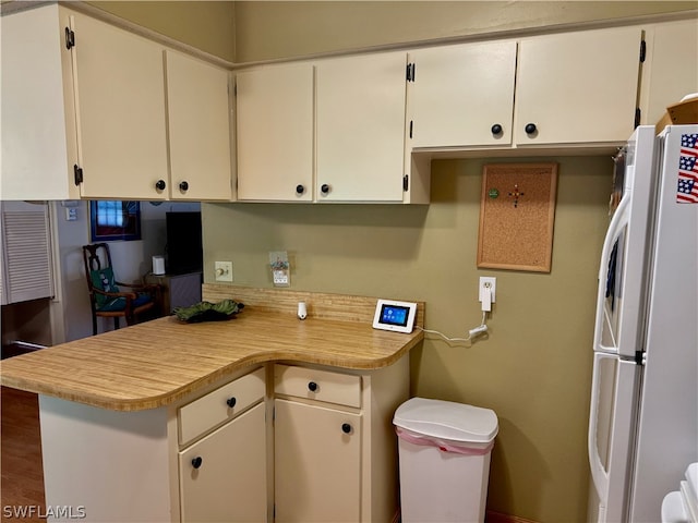 kitchen featuring white refrigerator, hardwood / wood-style floors, white cabinetry, and kitchen peninsula