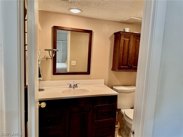 bathroom with a textured ceiling, toilet, and large vanity