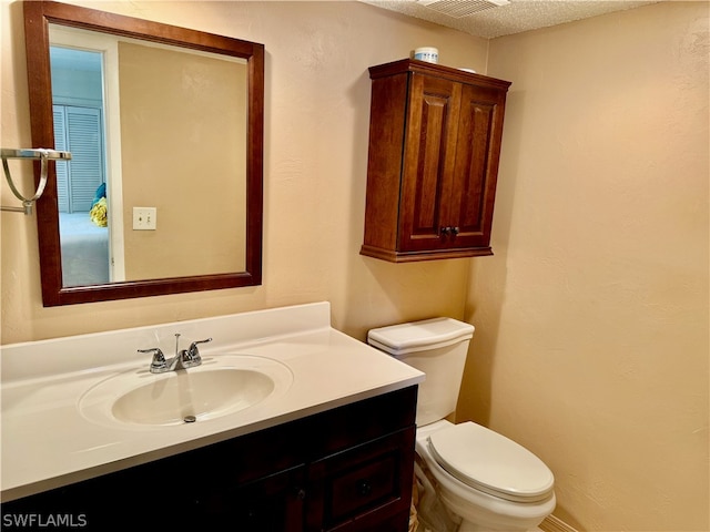 bathroom with a textured ceiling, toilet, and vanity