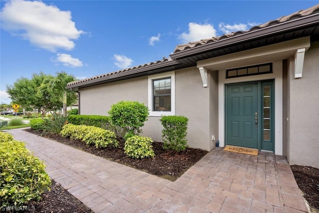 entrance to property with stucco siding and a tile roof