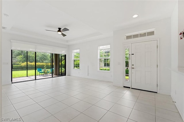 entrance foyer with light tile patterned flooring, baseboards, a raised ceiling, and a ceiling fan