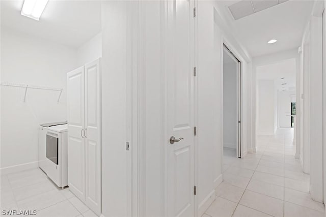 hall with light tile patterned floors, baseboards, and washer and clothes dryer