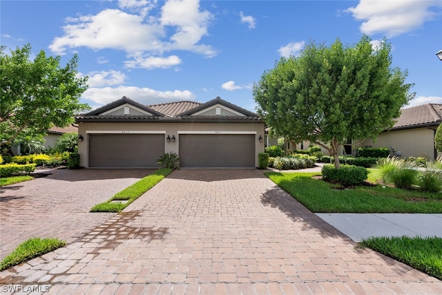 view of front of house with a tiled roof, decorative driveway, an attached garage, and stucco siding