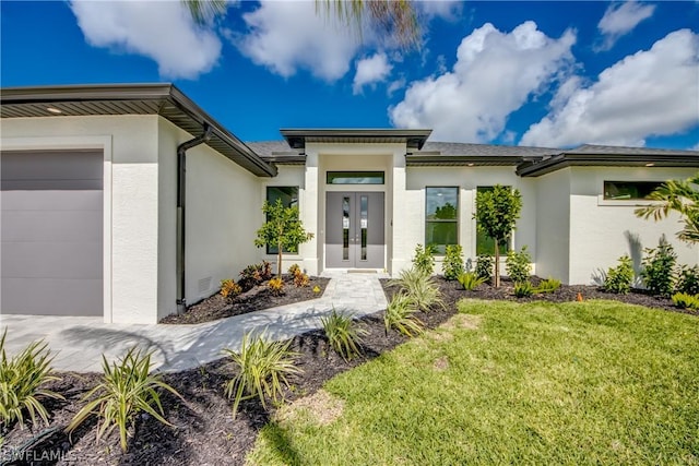 property entrance with a garage, a lawn, and french doors