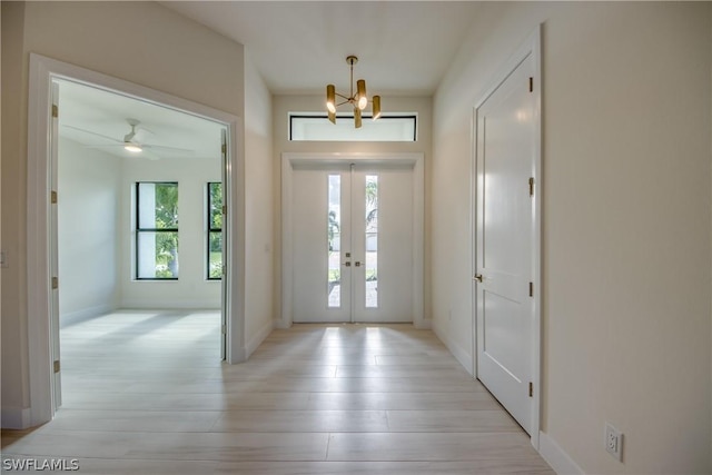 entrance foyer featuring french doors, an inviting chandelier, and light hardwood / wood-style floors