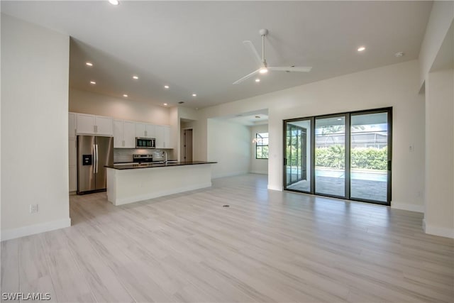 unfurnished living room with sink, ceiling fan, and light hardwood / wood-style flooring