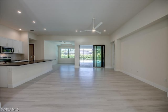 unfurnished living room featuring sink, ceiling fan, and light hardwood / wood-style flooring