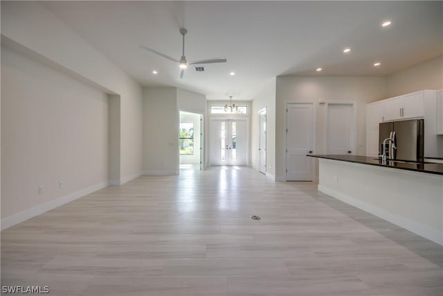 unfurnished living room featuring ceiling fan with notable chandelier, sink, and light hardwood / wood-style floors