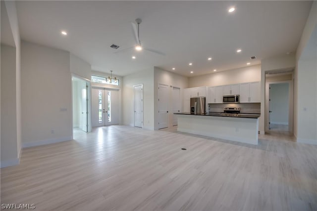 kitchen with french doors, appliances with stainless steel finishes, white cabinets, a center island with sink, and light hardwood / wood-style floors