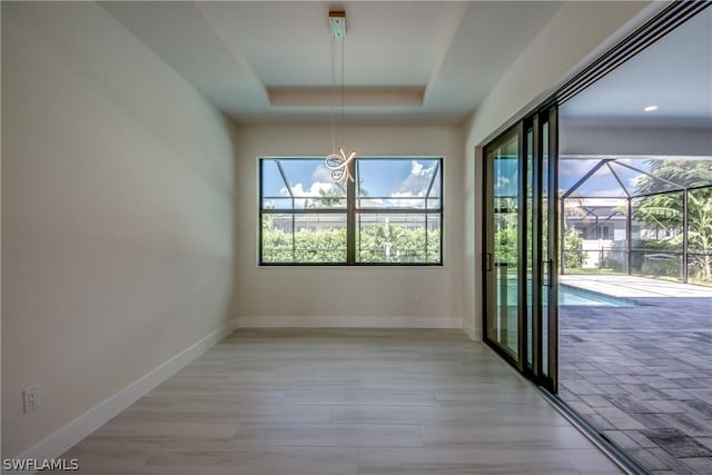 unfurnished dining area with a raised ceiling and light hardwood / wood-style floors