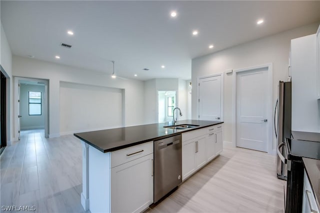 kitchen with light hardwood / wood-style flooring, appliances with stainless steel finishes, sink, white cabinets, and a kitchen island with sink