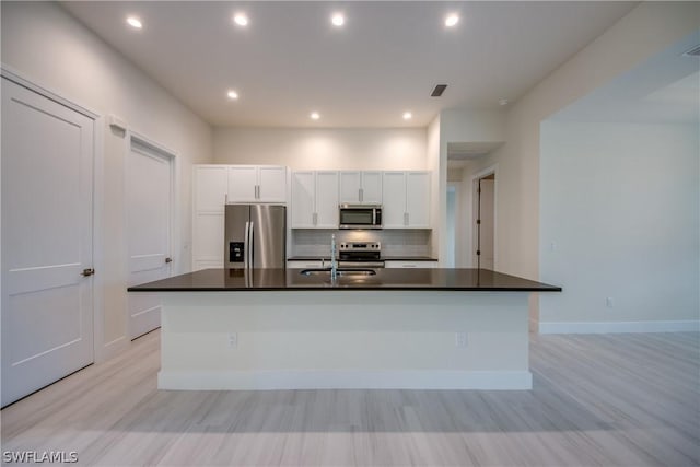 kitchen featuring white cabinets, stainless steel appliances, a kitchen island with sink, and sink