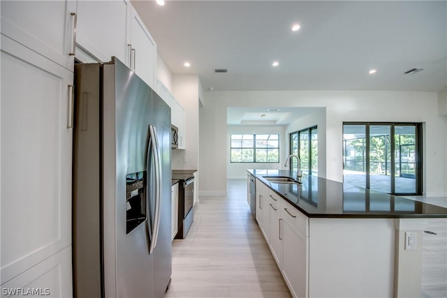 kitchen featuring a center island with sink, white cabinetry, and appliances with stainless steel finishes