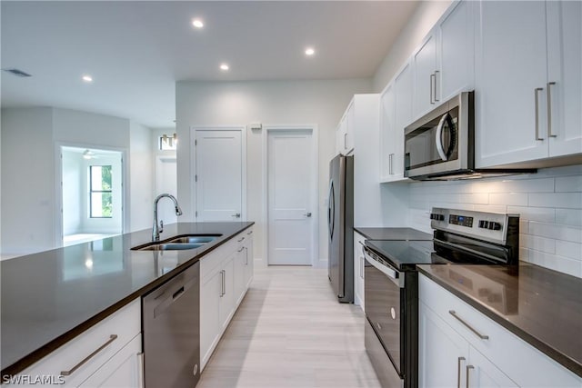 kitchen with sink, backsplash, white cabinetry, and stainless steel appliances