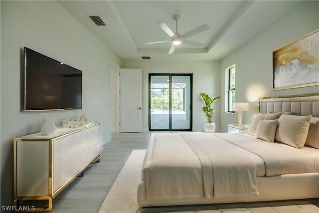 bedroom with access to exterior, ceiling fan, and a raised ceiling