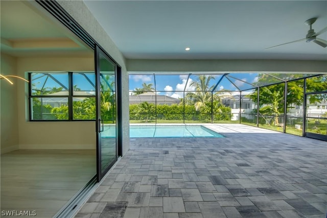 view of pool with glass enclosure, a patio area, and ceiling fan