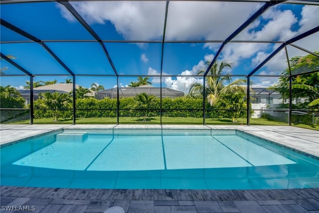 view of pool with glass enclosure, a patio area, and a yard