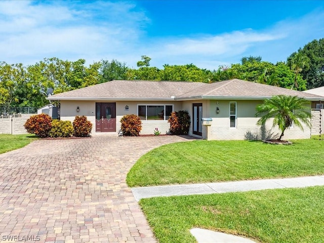 ranch-style home featuring a front lawn, brick siding, and stucco siding