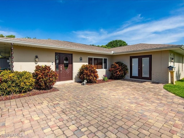 view of front facade with french doors, brick siding, and stucco siding