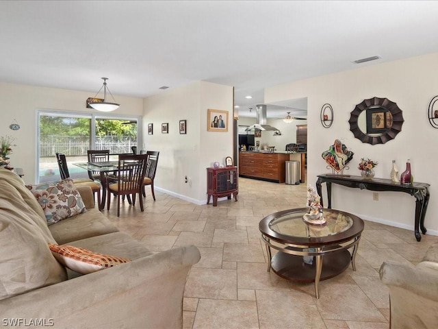 living area with recessed lighting, stone finish flooring, visible vents, and baseboards