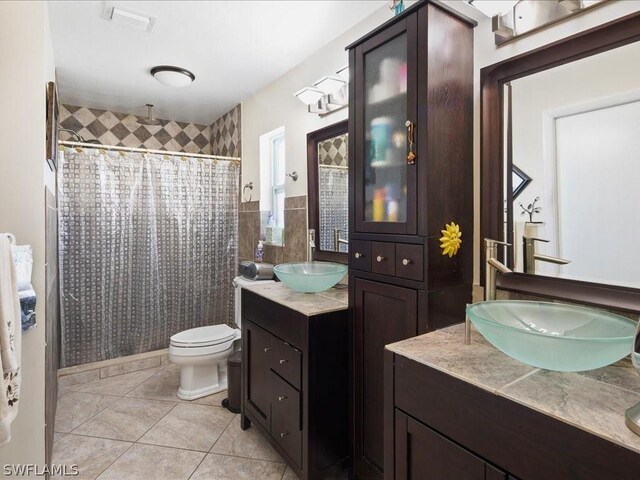 bathroom with tile patterned flooring, curtained shower, vanity, toilet, and tile walls