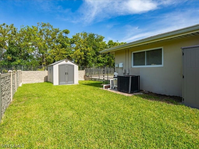 view of yard featuring an outbuilding, a fenced backyard, and a storage shed