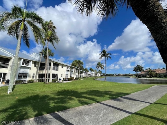 view of property's community with a lawn and a water view