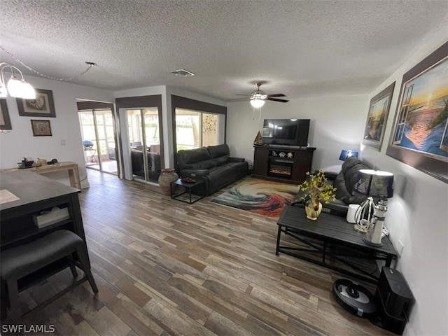 living room featuring ceiling fan, a textured ceiling, and dark hardwood / wood-style floors