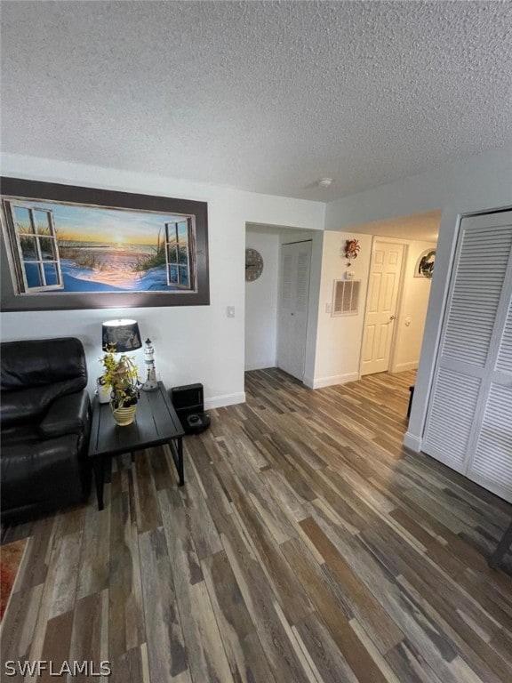 living room with a textured ceiling and dark hardwood / wood-style floors