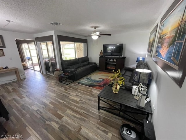 living room with ceiling fan, hardwood / wood-style flooring, and a textured ceiling