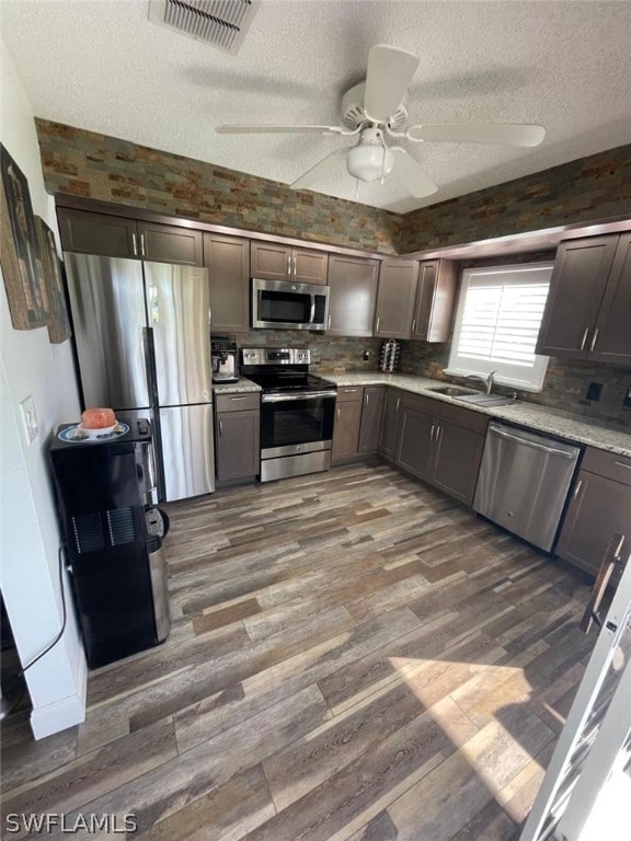 kitchen with dark brown cabinetry, ceiling fan, dark wood-type flooring, appliances with stainless steel finishes, and sink